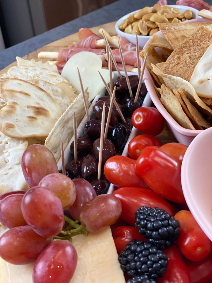 Close up of grapes, olives and cherry tomatoes on a grazing board