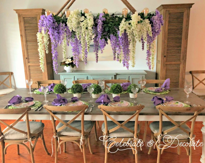 Wisteria hanging over a table set with floral plates and lavender napkins