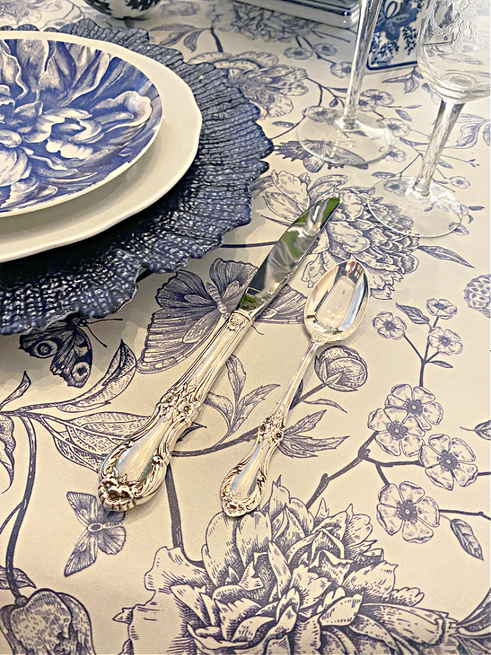 Detail of blue and white floral tablecloth and sterling silver flatware
