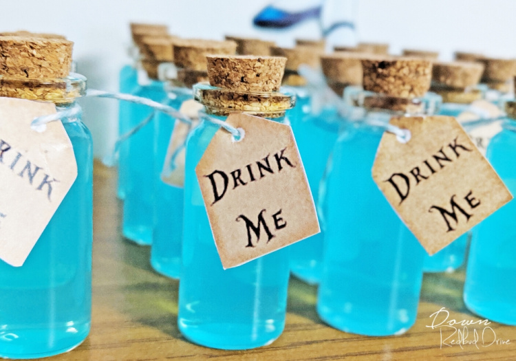 Tiny bottles with blue juice and Drink Me tags on them for an Alice in Wonderland party