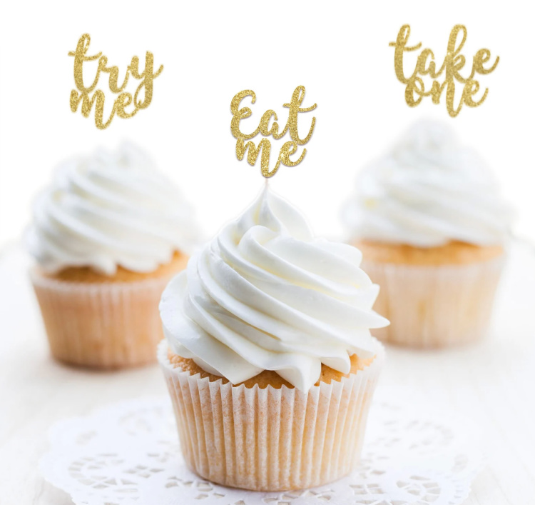 White cupcakes with white frosting and gold Eat Me tags on top of them