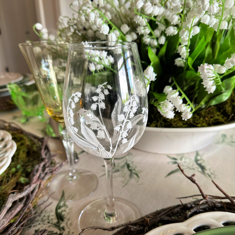 A wine glass with lily of the valley on it.