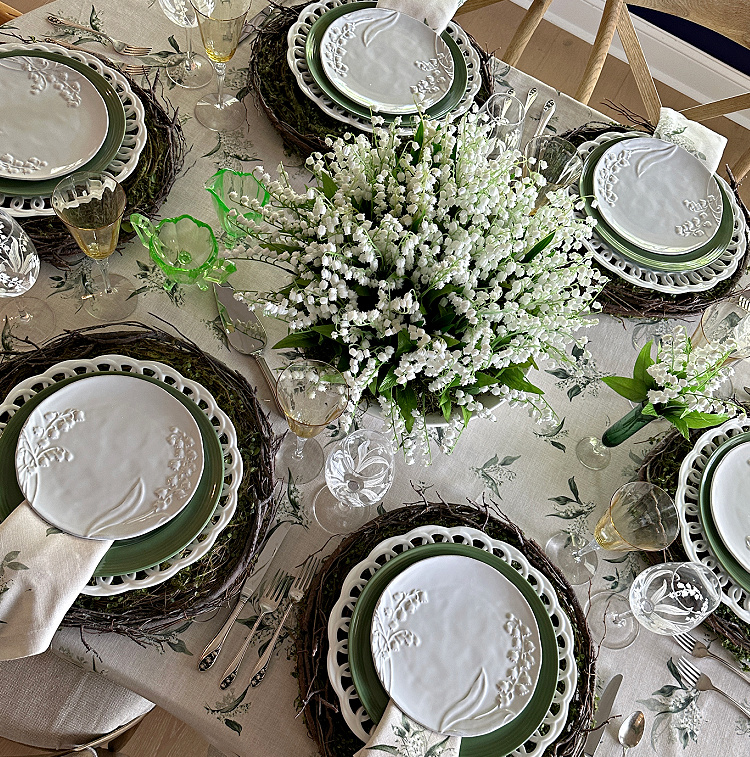Overhead view of a table set with lily of the valley salad plates and a centerpiece of lily of the valley plants