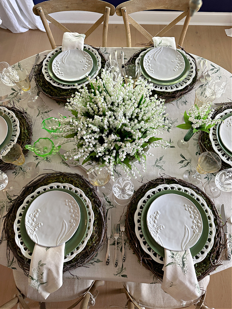 Overhead view of a centerpiece full of lily of the valley and the rest of the tabletop done in green and white.  