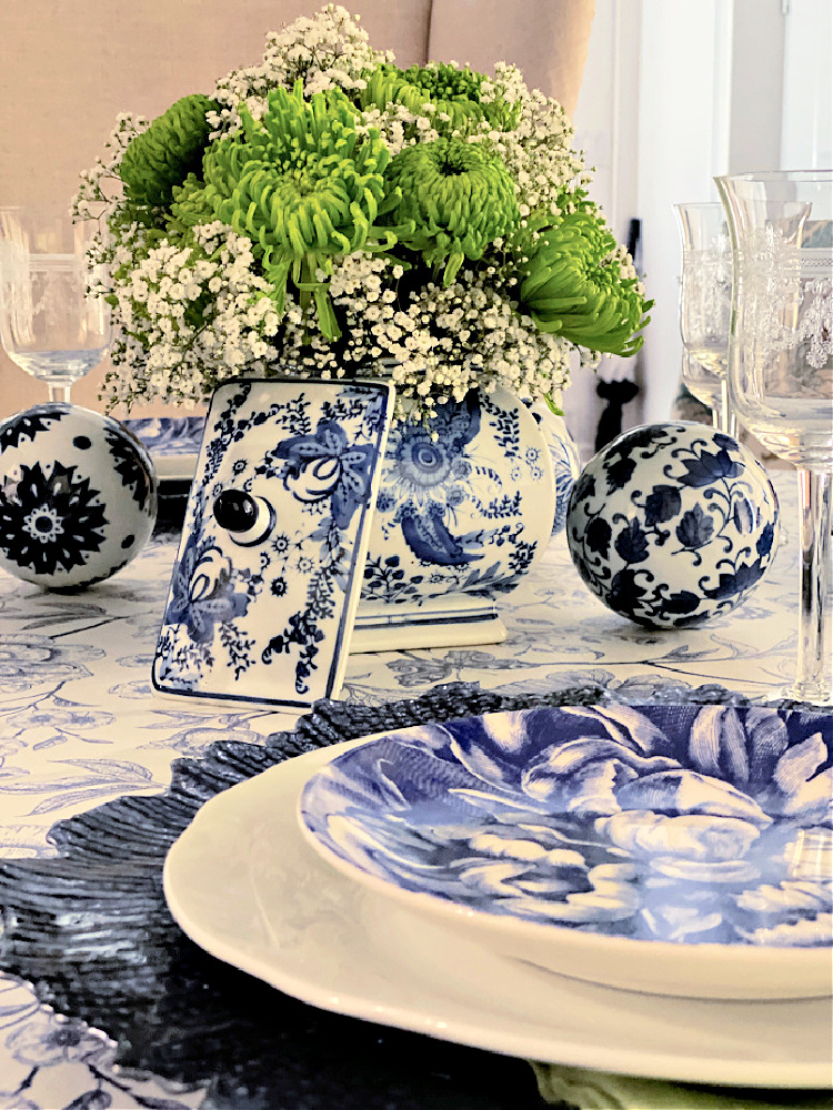 A blue and white tablescape with a chinoiserie container filled with green chrysanthemums. 