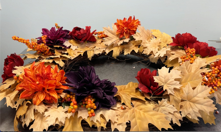Golden maple leaf wreath with bittersweet berry clusters and fall colored flowers.
