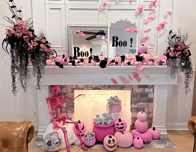 PInk and black halloween decor on a mantel and in a fireplace