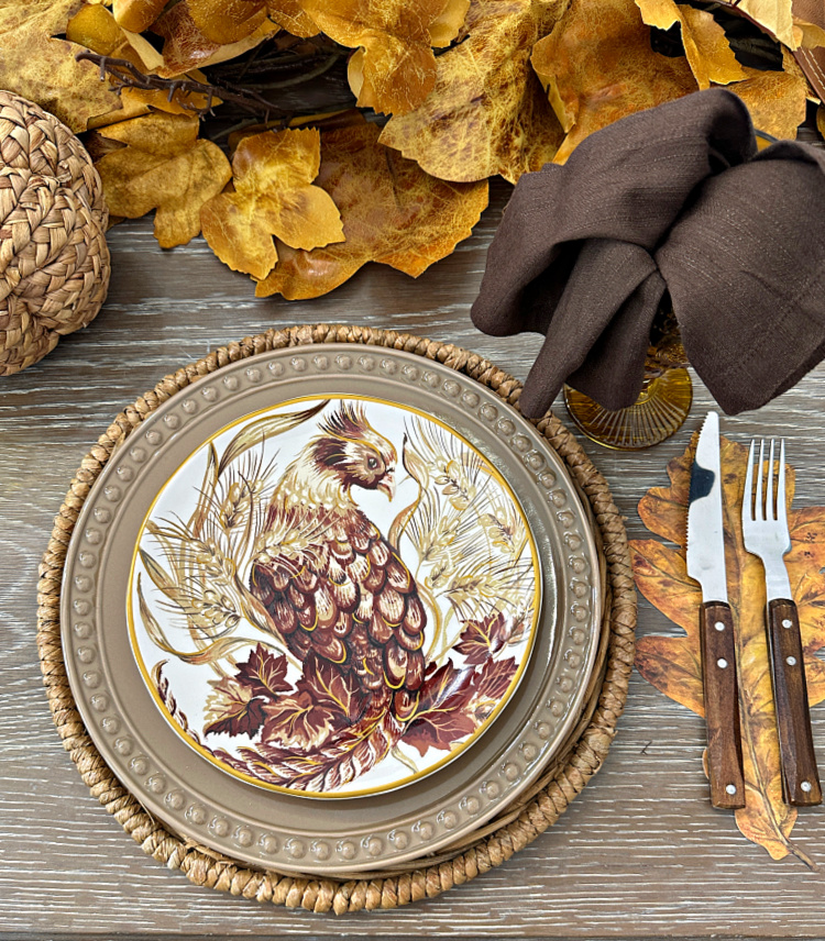 A place setting with a salad plate with a stylized pheasant on it.
