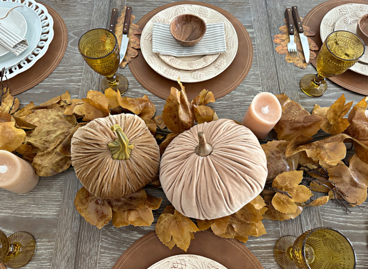 A Neutral fall centerpiece with brown leaves and velvet pumpkins.