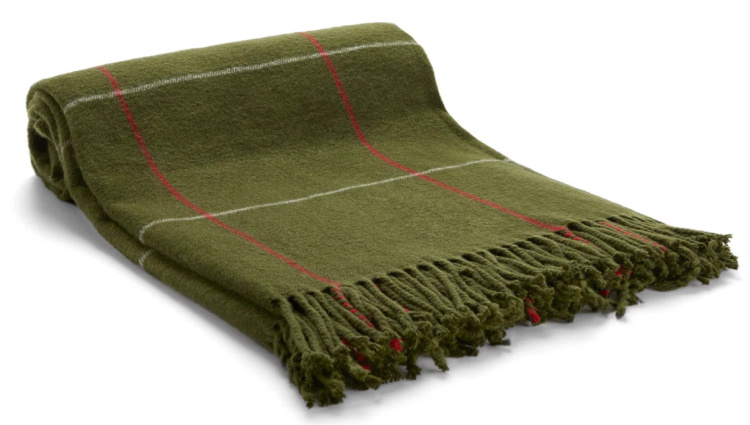 Olive green woven throw blanket with fringe detail, perfect for adding warmth and texture to late summer and early fall decorating.