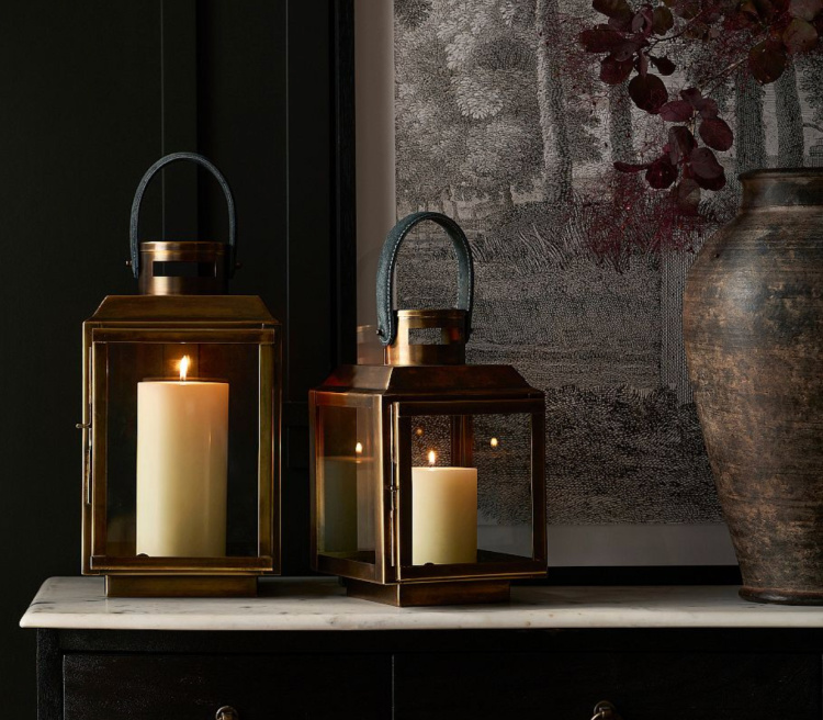 Pair of brass lanterns with glowing pillar candles styled on a marble console table, creating a warm and inviting display for late summer decorating.
