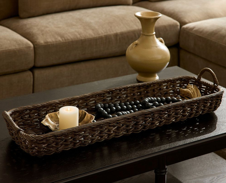 Dark woven wicker tray styled with a candle, wood bead garland, and ceramic vase on a coffee table for elegant late summer decorating.