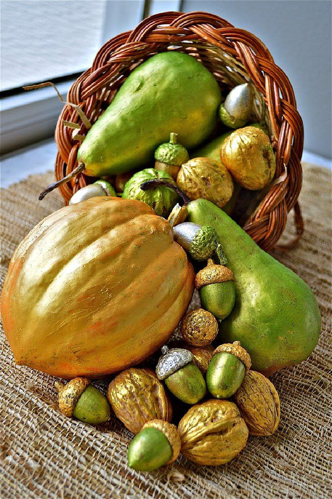 Gilded pears, walnuts, acorns, and an acorn squash arranged as Thanksgiving decorations.