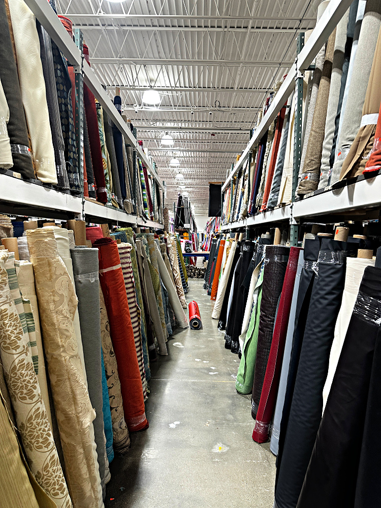 Huge selection of upholstery fabrics on display at a fabric store, with a wide variety of colors, patterns, and textures to choose from.